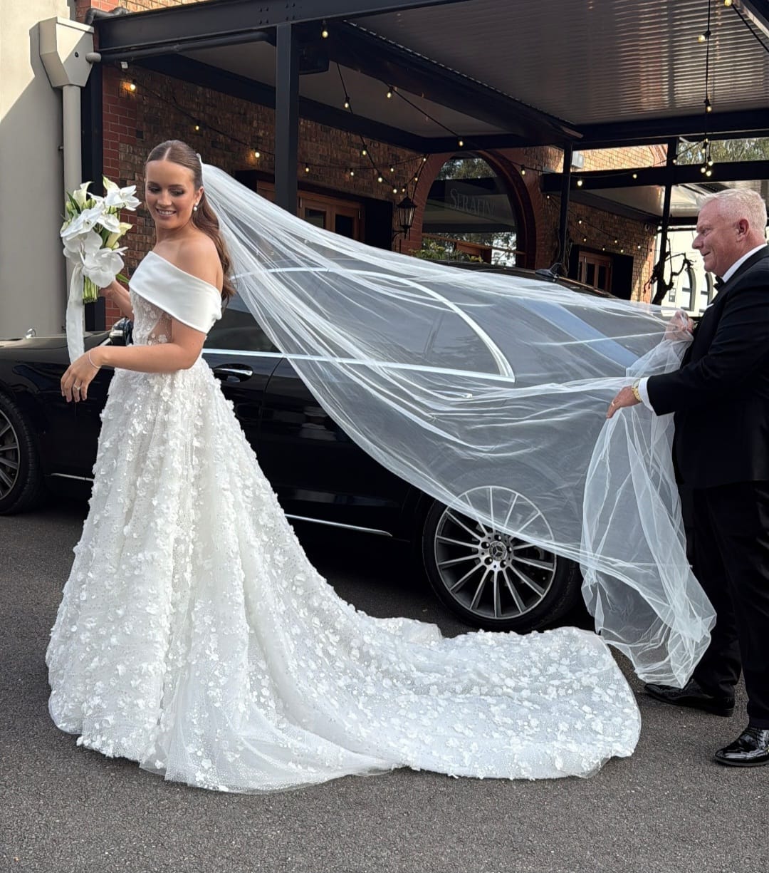 Bride arriving at wedding venue with chauffeur assistance